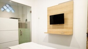 A modern bedroom with a bed, a wardrobe, a mirror, and a mounted TV. - PBINN Tamastu House Pasar Baru (Jakarta)