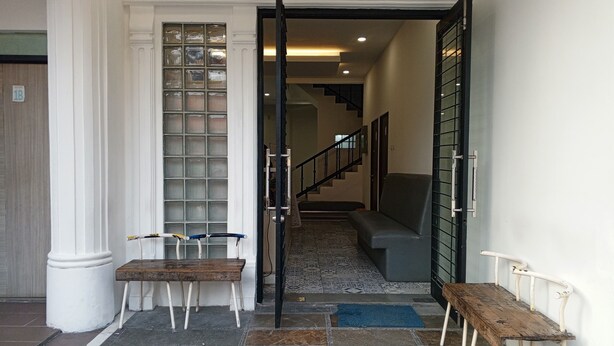 A hotel entrance with a tiled floor, a bench, a door, and a staircase leading to the upper floors. - PBINN Tamastu House Pasar Baru (Jakarta)