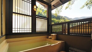 Un onsen japonais traditionnel, avec une baignoire en bois, des portes coulissantes et une vue sur les montagnes.