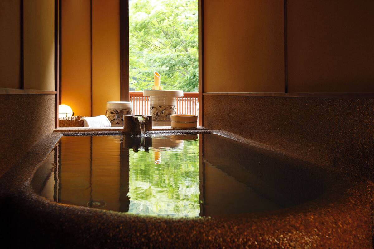 Baño de aguas termales con vistas a árboles a través de una ventana.