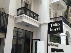 Entrada d'hotel amb un rètol que diu 'Tulip Hotel' i un balcó amb baranes negres.
