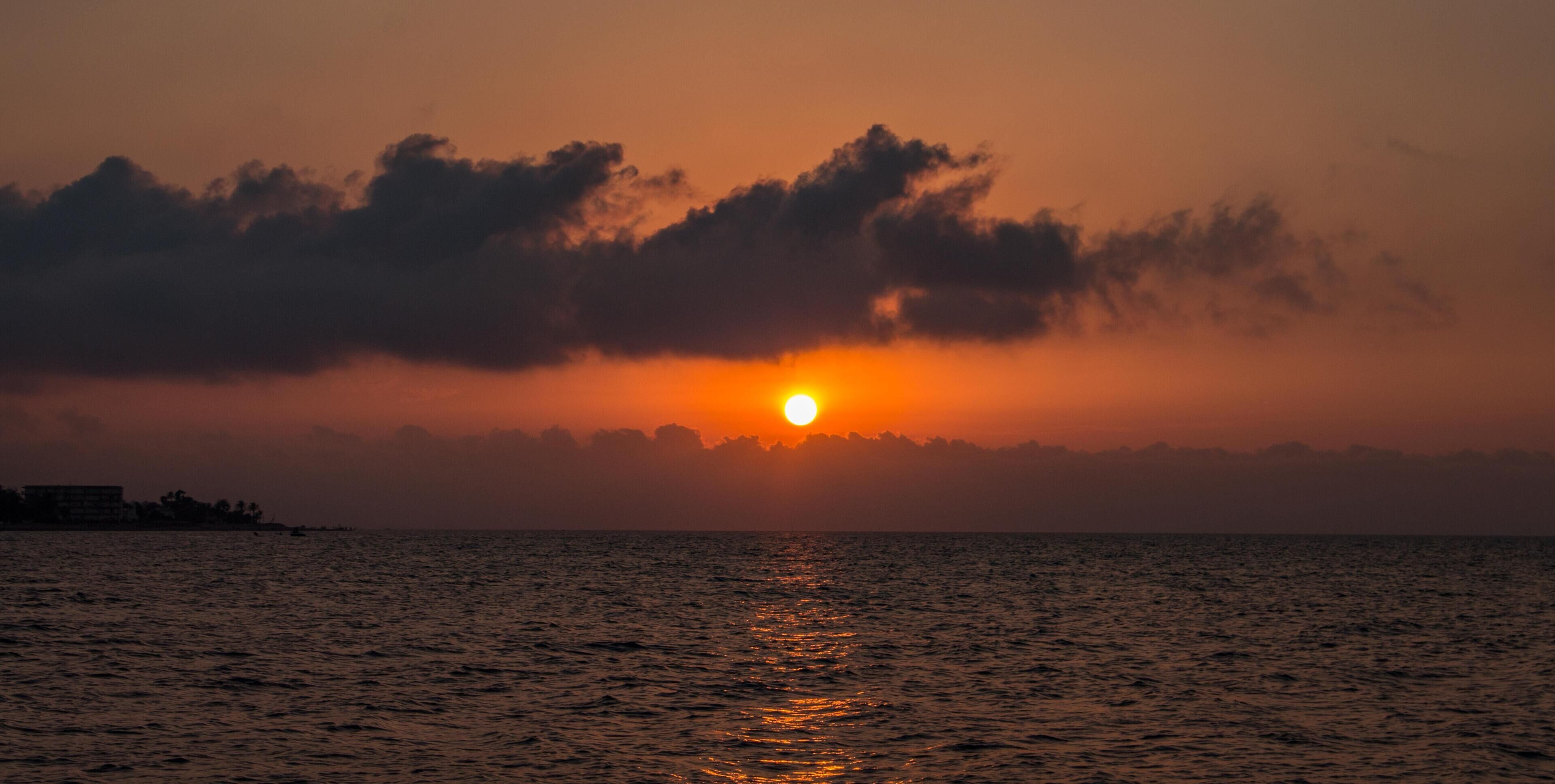 A sunset over a body of water with clouds in the sky.