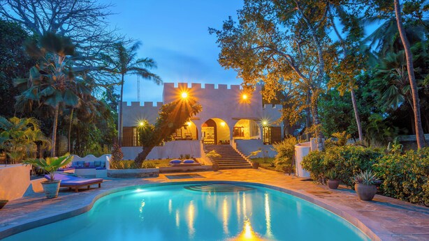 A pool with a castle-like structure in the background, surrounded by tropical vegetation. - Marula House 3BD, Diani Beach (Diani Beach)