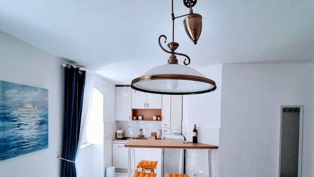 Une cuisine moderne avec des meubles blancs, un plan de travail en bois et deux tabourets orange.