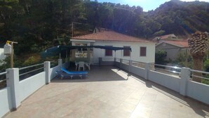 Una casa con un patio empedrado, una mesa con sillas y una sillón azul.