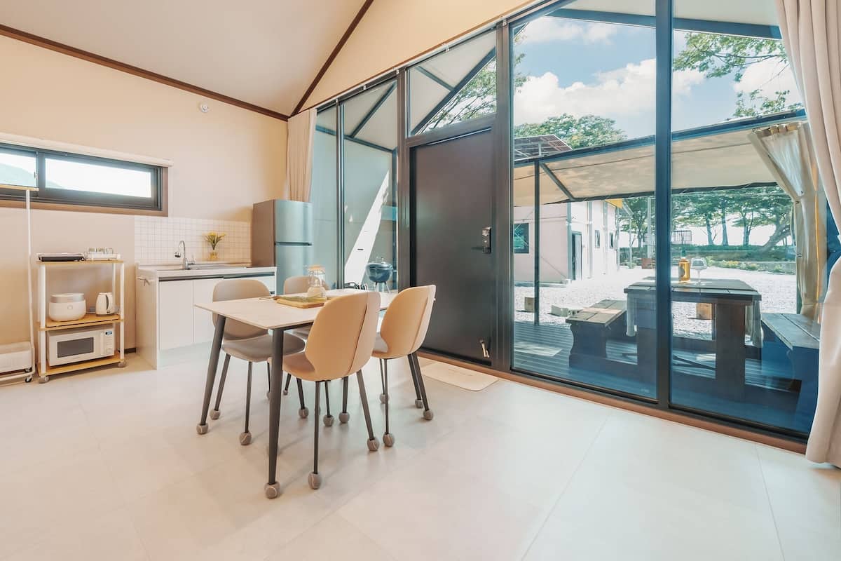 A modern hotel room with a dining area, kitchenette, and large sliding glass doors to an outdoor patio.