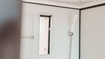 A modern bathroom with a glass shower enclosure, a handheld showerhead, and a door with a handle.