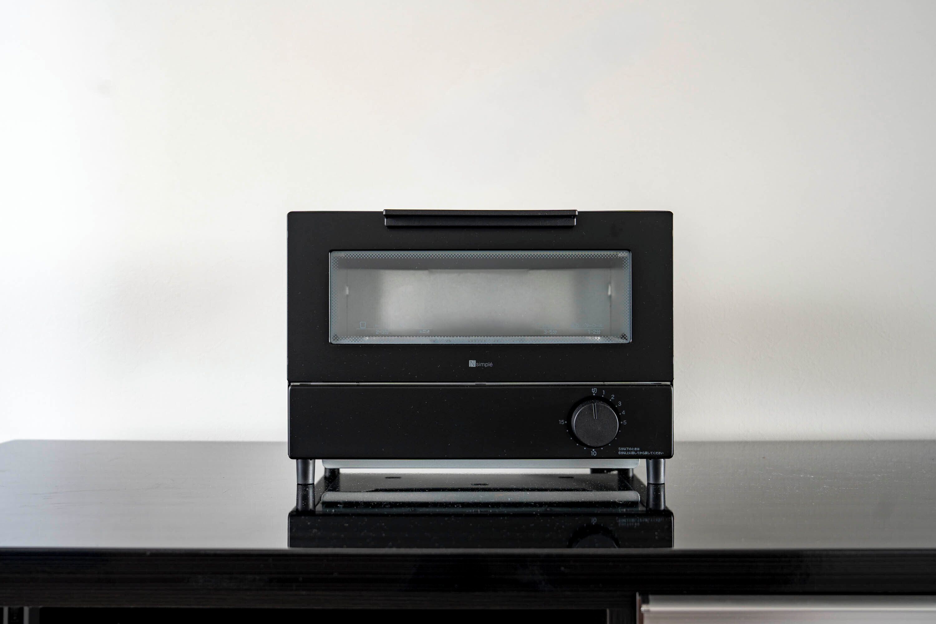 A black electronic device with a screen and a control knob on a reflective surface.