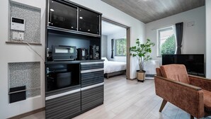 A modern room with a kitchenette, a bed, a TV, and a plant. - MKS201 (Asahikawa)