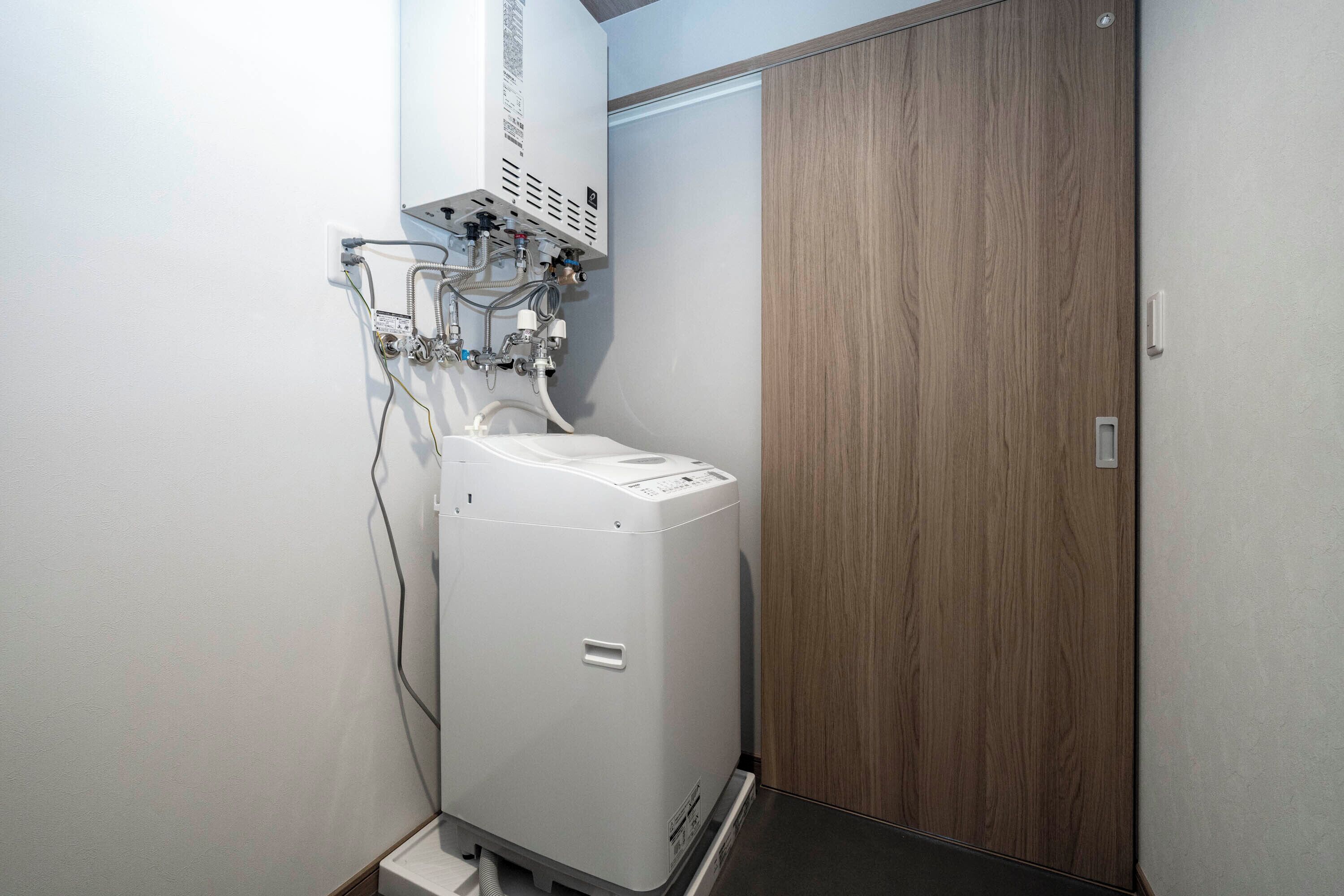 A compact room with a white air conditioning unit, a wooden door, and a white wall.