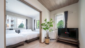 A modern hotel room with two beds, a large window, a flat-screen TV, and a potted plant. - MKS201 (Asahikawa)