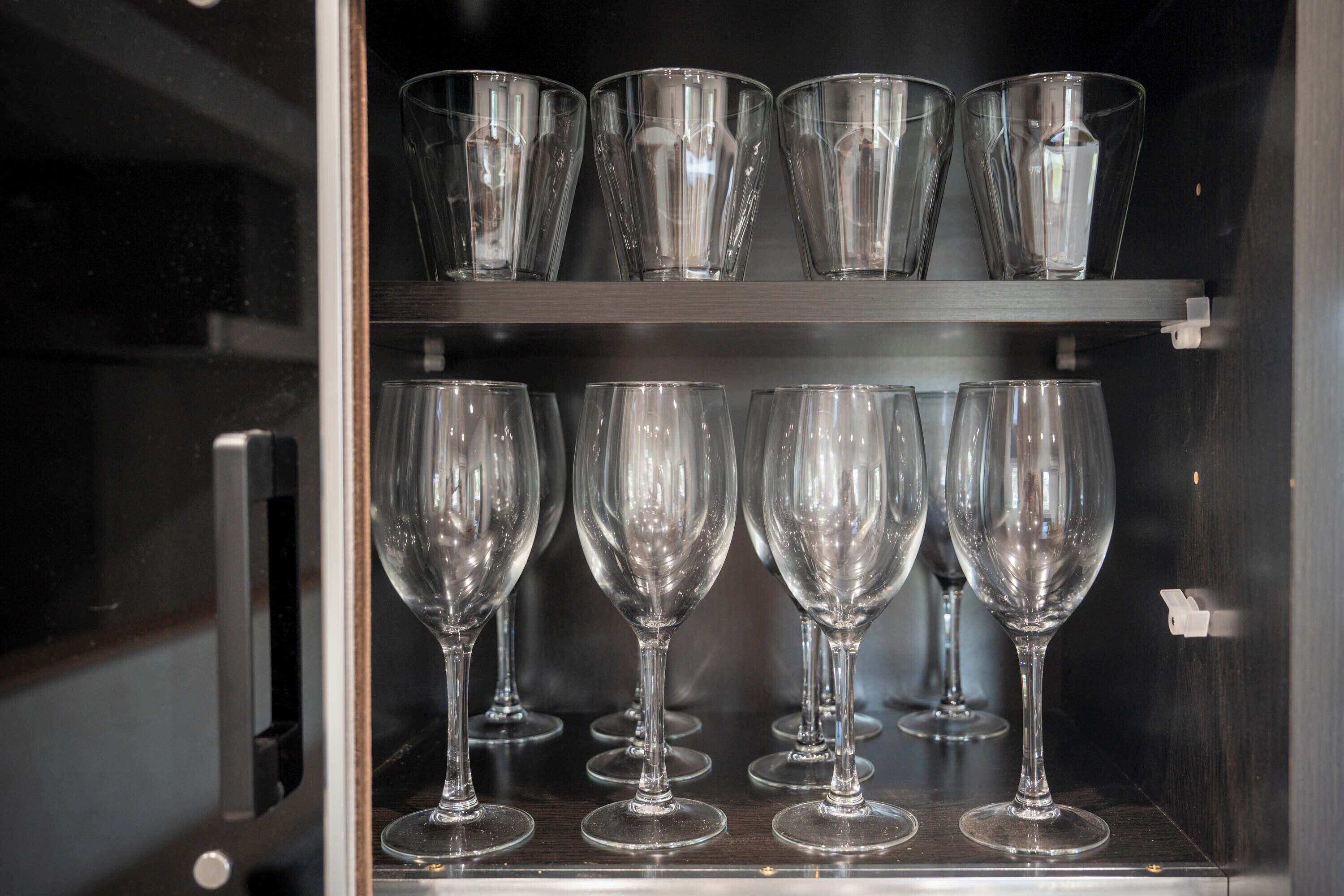 A glass display case with multiple wine glasses and tumblers.