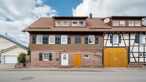 A two-story building with a traditional facade, a wooden door, and a garage door. - Apartment 'Malia' with Shared Terrace, Shared Garden and Wi-Fi (Neubulach)