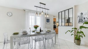 A modern dining area with a clear glass table, metal chairs, and pendant lighting. - Villa Safari Golf & Spa - Toulouse - prox. Airbus (Plaisance-du-Touch)