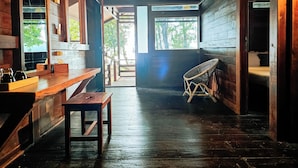 A wooden interior with a wooden bench, a chair, and a table. - ANDAU DIVE RESORT - RAJA AMPAT (Miosandau Kecil Island)