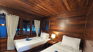 A room with two beds, wooden walls, and a window with curtains. - ANDAU DIVE RESORT - RAJA AMPAT (Miosandau Kecil Island)