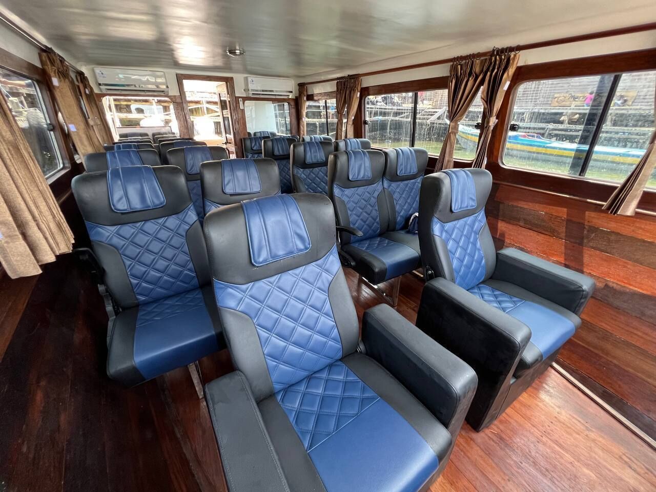A row of blue and black upholstered seats with quilted patterns, arranged in a cabin with wooden flooring and large windows.
