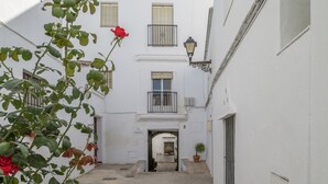 Un estrecho callejón con un edificio blanco, un balcón y una planta en maceta.
