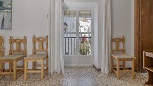 Una habitación con vistas, con sillas de madera, un cuadro y suelo de baldosas.