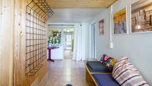 A hallway with a wooden wall, a metal rack, a sofa with patterned cushions, and framed artwork on the wall. - Holiday Apartment 'Silvi und Heinz Huber' in Durbach, Traditional Timber-Framed House (Durbach)