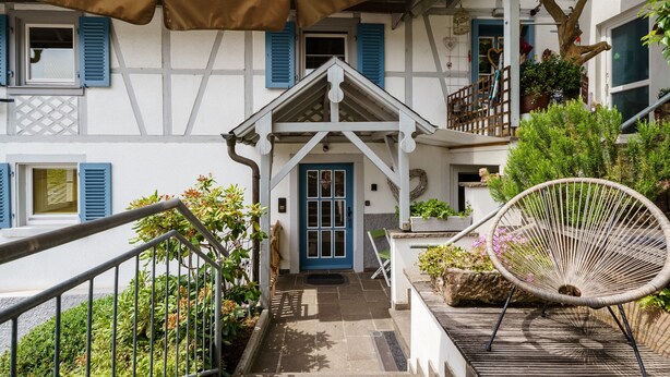 A traditional European-style building with a central entrance, a wooden chair, and a staircase leading to an upper level. - Holiday Apartment 'Silvi und Heinz Huber' in Durbach, Traditional Timber-Framed House (Durbach)