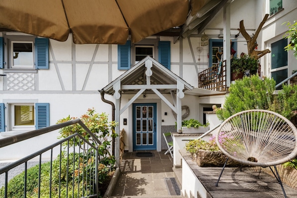 A traditional European-style building with a central entrance, a wooden chair, and a staircase leading to an upper level.