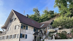 A traditional half-timbered house with a steeply pitched roof, a visible chimney, and a small front porch. - Holiday Apartment 'Silvi und Heinz Huber' in Durbach, Traditional Timber-Framed House (Durbach)