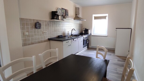 A kitchen with a black countertop, white cabinets, and a window. - Apartment Wernerstr in the center - 3 bedrooms (Cottbus)