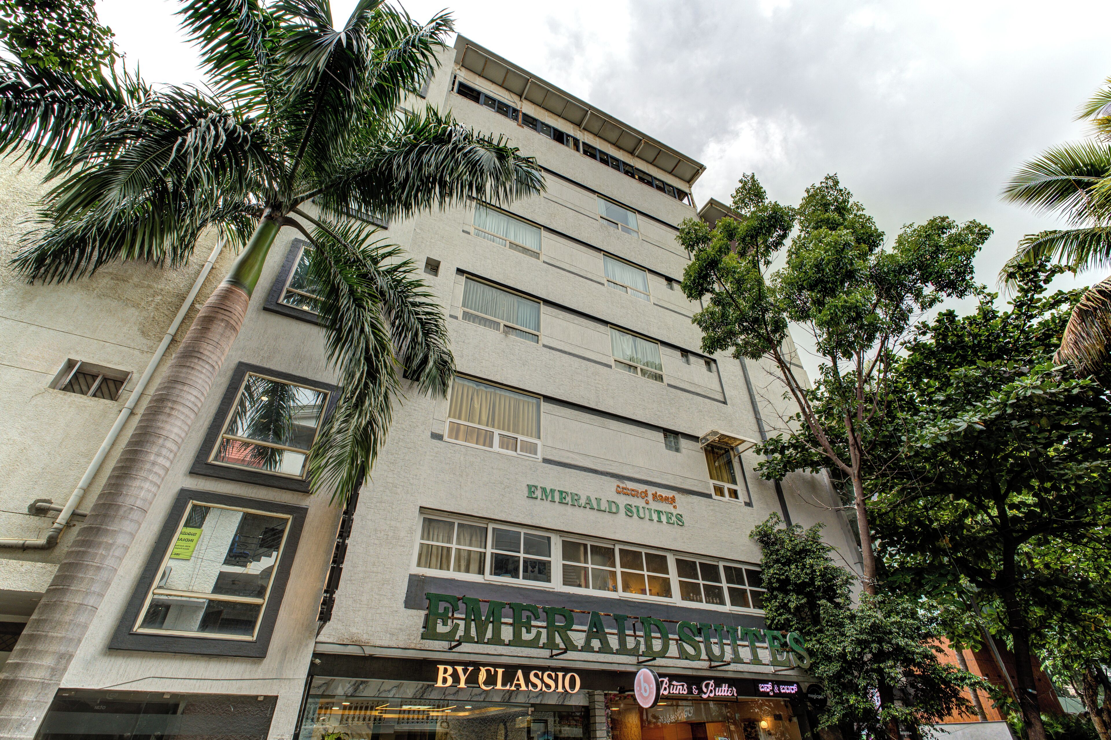 Un immeuble à plusieurs étages, avec une enseigne indiquant « Emerald Suites » et un établissement « By Classio ».