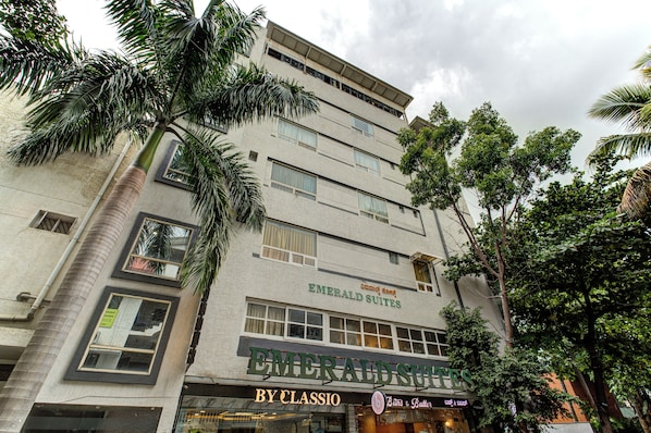 Un edificio de varios pisos con un letrero que dice 'Emerald Suites' y un establecimiento 'By Classio'.