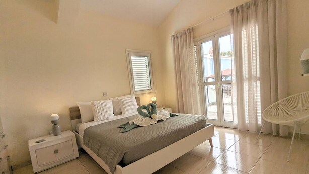 Un dormitorio con cama, mesita de noche y una silla.