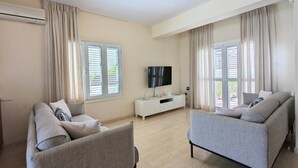 Una sala de estar moderna con dos sofás grises, un mueble de televisión blanco y un accesorio de iluminación en el techo.