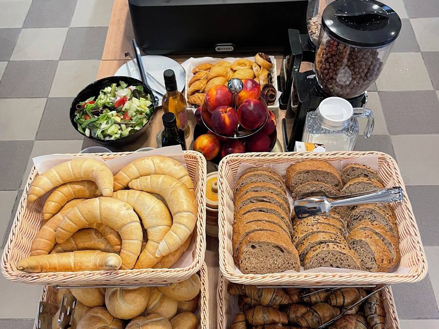 A buffet table with various food items including hot dogs, macaroni and cheese, and pastries.
