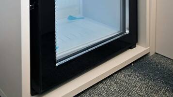 A compact refrigerator with a glass door, a control panel, and a water dispenser.