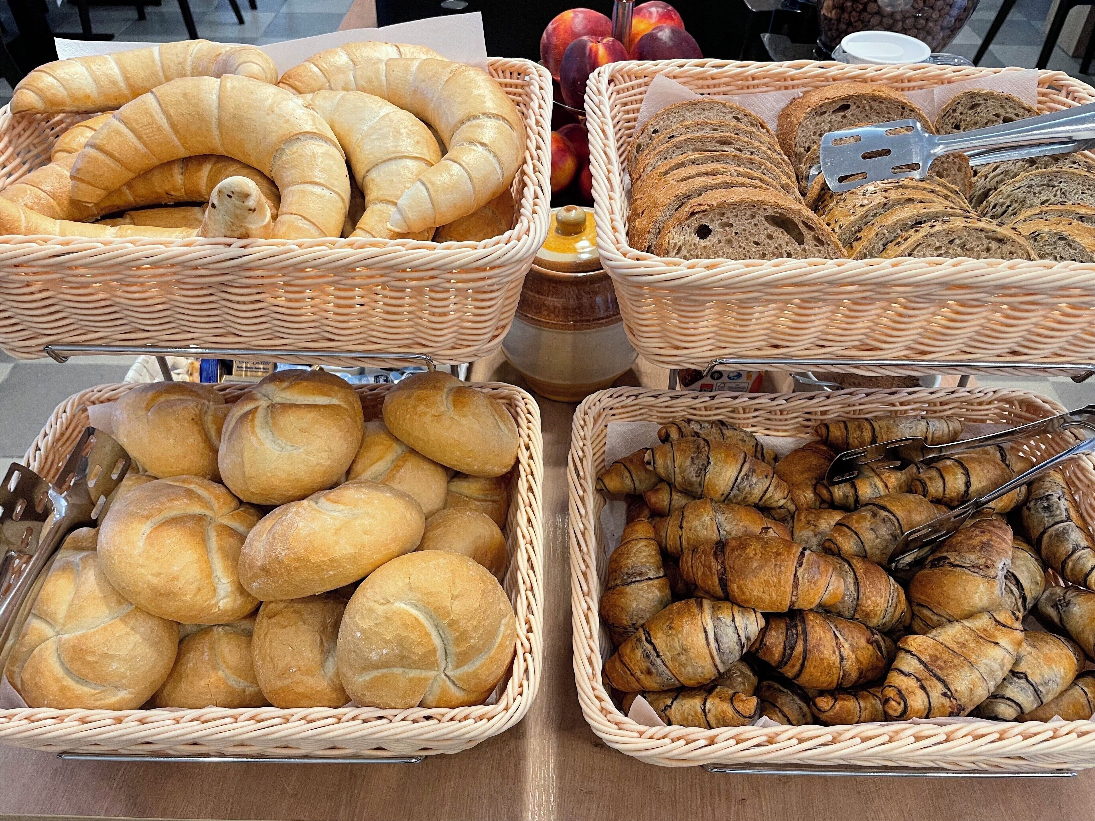 Un tavolo con quattro cesti di vimini pieni di pane e dolci.