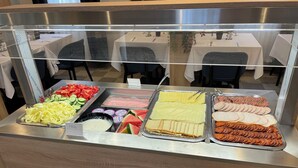 Un buffet con diverse opzioni di cibo, tra cui pasta, insalate e carni.