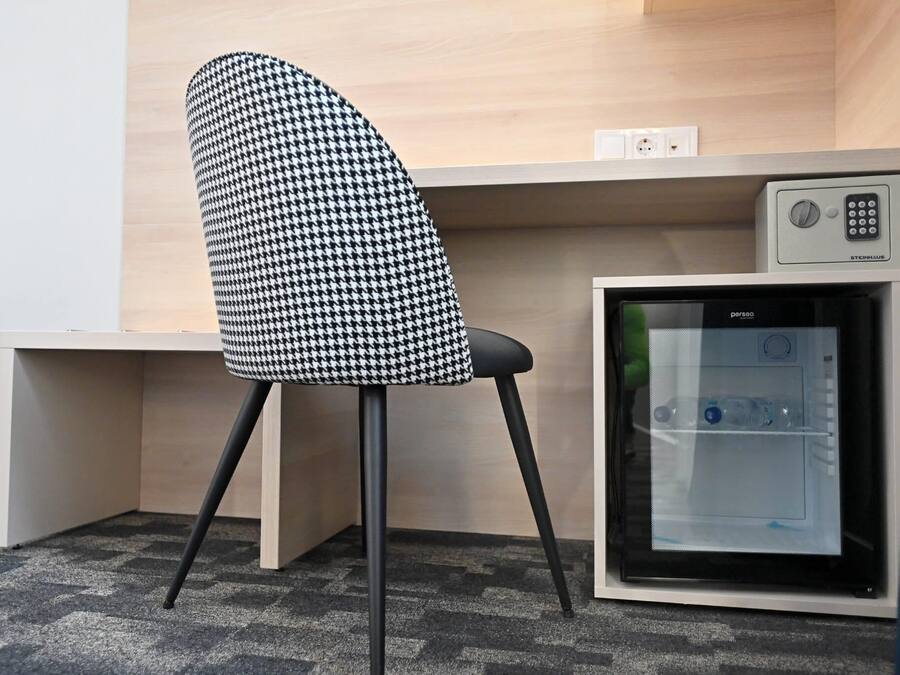 Una silla de oficina moderna con estampado de piedritas, un escritorio de madera y un refrigerador integrado.