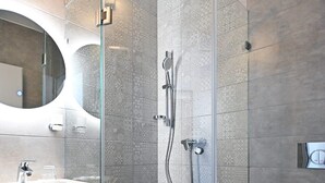 Un bagno moderno con cabina doccia in vetro, lavandino con specchio e WC.
