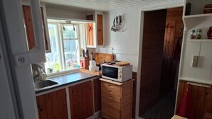 Una cocina compacta con armarios de madera, un microondas y un lavamanos.