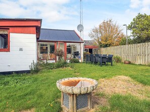 Una propiedad residencial con antena parabólica, patio trasero cercado y un bebedero de piedra para pájaros.