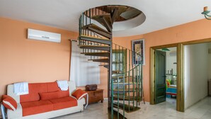 A living room with a spiral staircase, a sofa, a small table, and a window.
