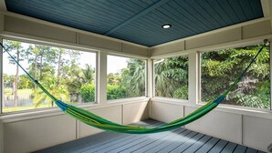 A hammock in a room with large windows and a blue ceiling. - Paradise Palm River House w/  WATERFRONT OCEAN ACCESS & PRIVATE POOL AND DOCK (Stuart)