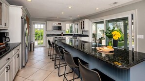 A modern kitchen with a large island, bar stools, and a view of the outdoors. - Paradise Palm River House w/  WATERFRONT OCEAN ACCESS & PRIVATE POOL AND DOCK (Stuart)