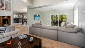 A spacious living room with a large gray sectional sofa, a wooden coffee table, and a dining area in the background. - Paradise Palm River House w/  WATERFRONT OCEAN ACCESS & PRIVATE POOL AND DOCK (Stuart)