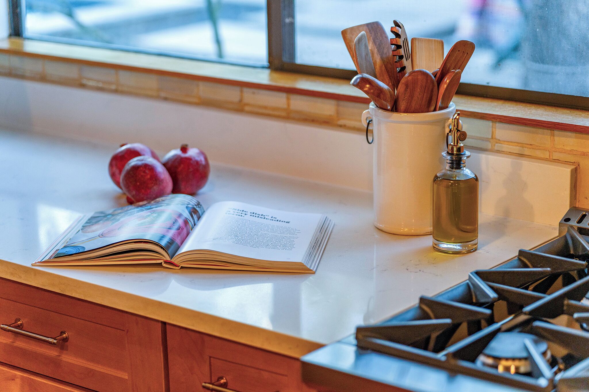 A kitchen counter with a magazine, a bottle, and wooden utensils.