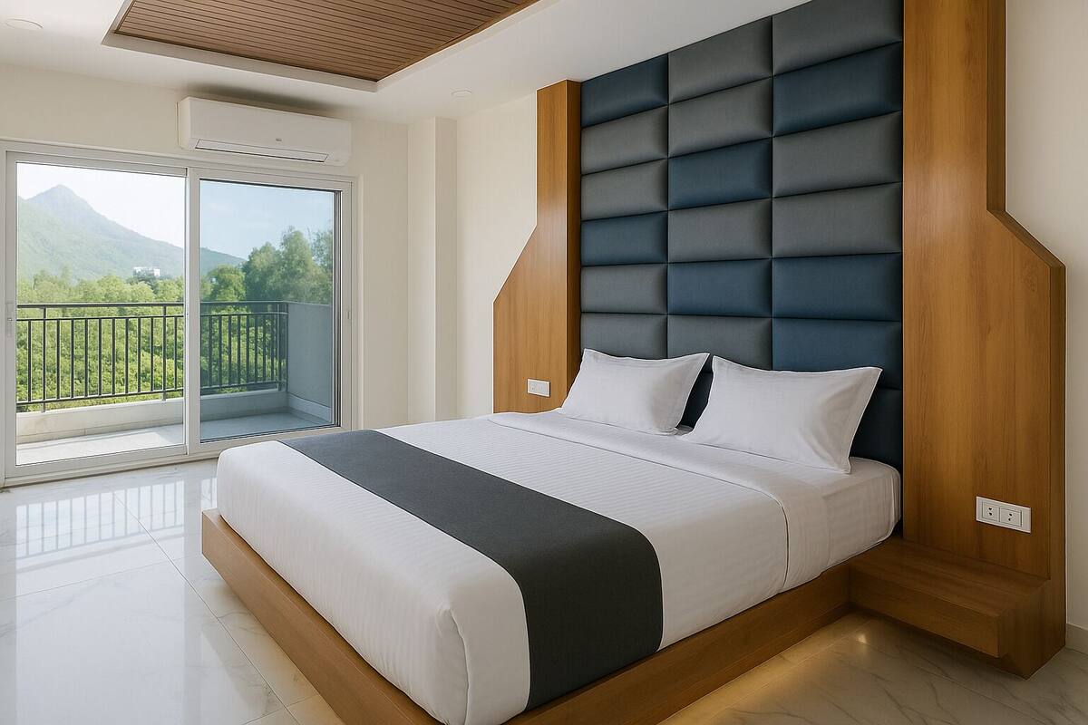 A modern bedroom with a large bed, a wooden headboard, and a balcony with a mountain view.