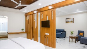 A modern hotel room with a bed, a TV, a sofa, and a chair. - HOTEL KARDHAR INN (Ambaji)