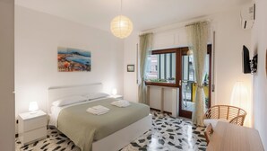 A bedroom with a bed, bedside tables, a painting, a window with curtains, and a view of the outside. - 323 Cilea Apartment (Napoli)