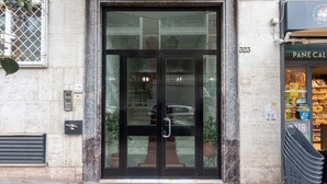 A building entrance with a glass door, a number '323' on the wall, and a store with a sign 'PANE CALLE' visible through the window. - 323 Cilea Apartment (Napoli)