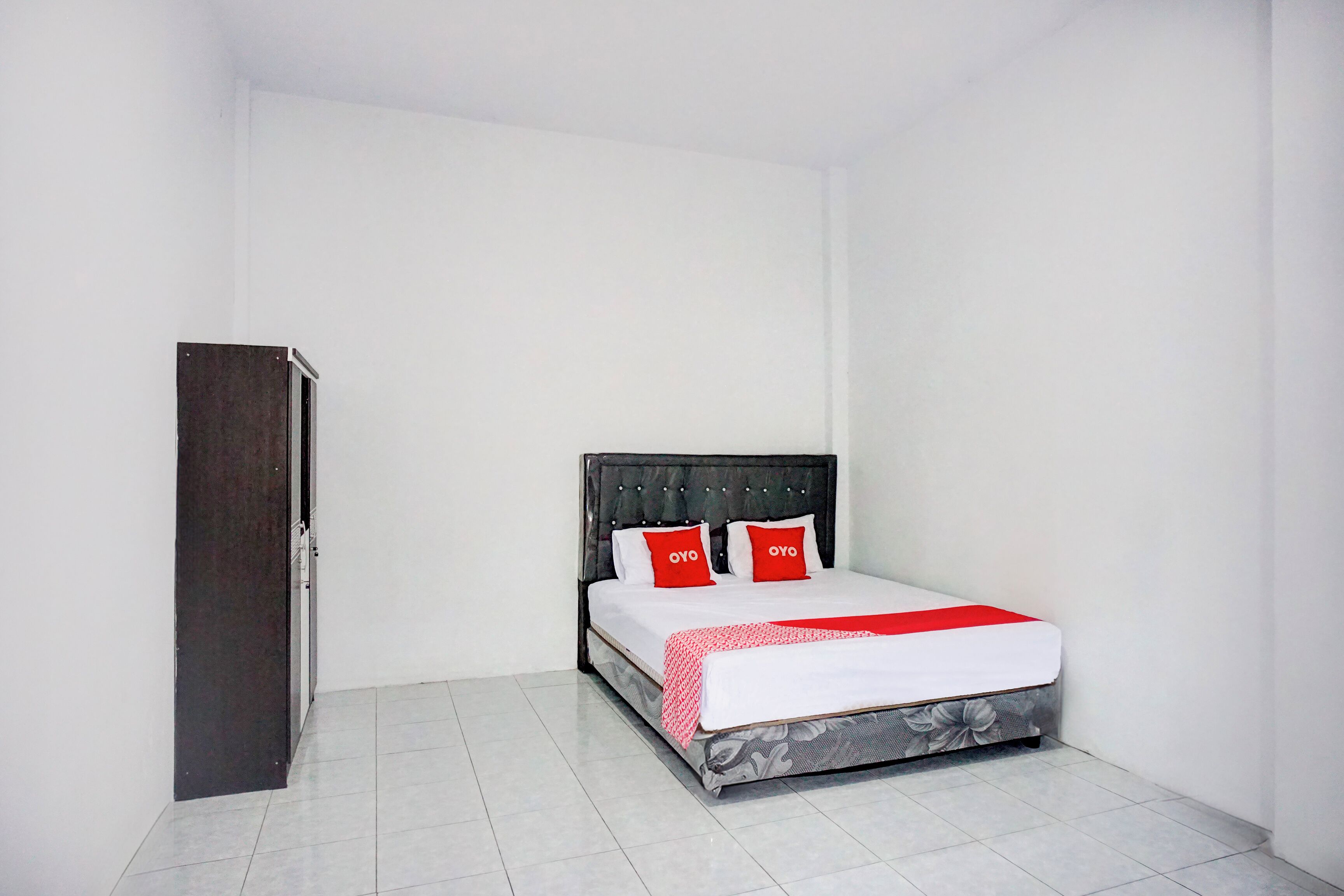 Una camera da letto con un letto, un armadio e pavimento piastrellato.